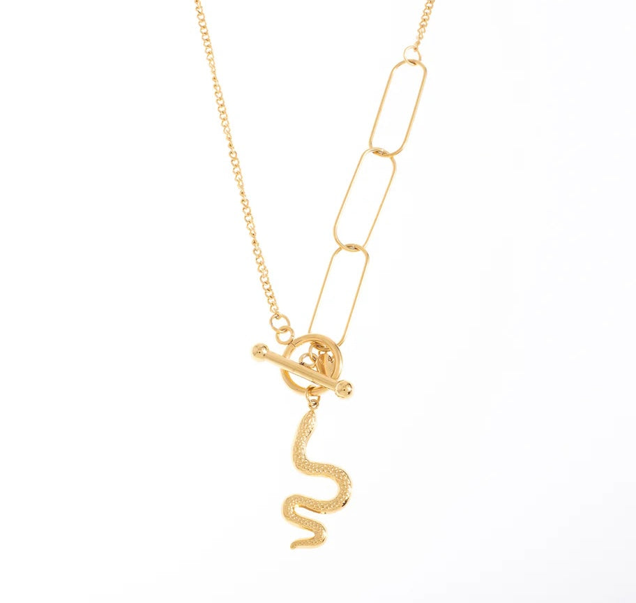 Opte pour l'audace avec ce collier, acier inoxydable et plaqué or, qui sort vraiment de l'ordinaire. Son design asymétrique combine une chaîne classique à maillons fins avec des maillons géométriques plus larges, créant un contraste élégant et contemporain. Le véritable point fort ? Le pendentif serpent texturé qui ajoute une touche mystique et rebelle à l'ensemble. Le fermoir en T, sur le devant du bijou, parfaitement intégré au design, apporte une touche finale sophistiquée.