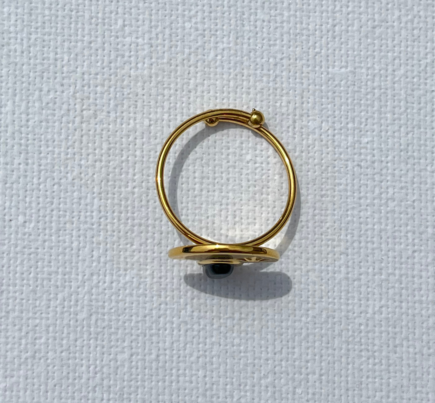 Découvre notre bague demi-lune, en acier inoxydable et plaqué or. Cette bague unique affiche une pierre noire en cabochon, parfaitement nichée sous une plaque dorée gravée d'une étoile. Le contraste saisissant entre l'éclat doré et la profondeur de la pierre noire apportera une dimension chic à toutes tes tenues. Ajustable et confortable, ce bijou est parfait si tu veux allier sophistication et originalité.