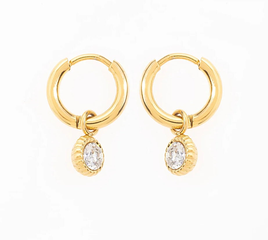 Craque pour ces élégantes boucles d'oreilles créoles, en acier inoxydable et plaqué or, qui sublimeront ton look en un clin d'œil. Chaque anneau arbore un pendentif délicatement serti d'une pierre de zirconium. Adopte-les pour briller en toutes circonstances, et laisse ces créoles rehausser ton style avec une pointe d’élégance.