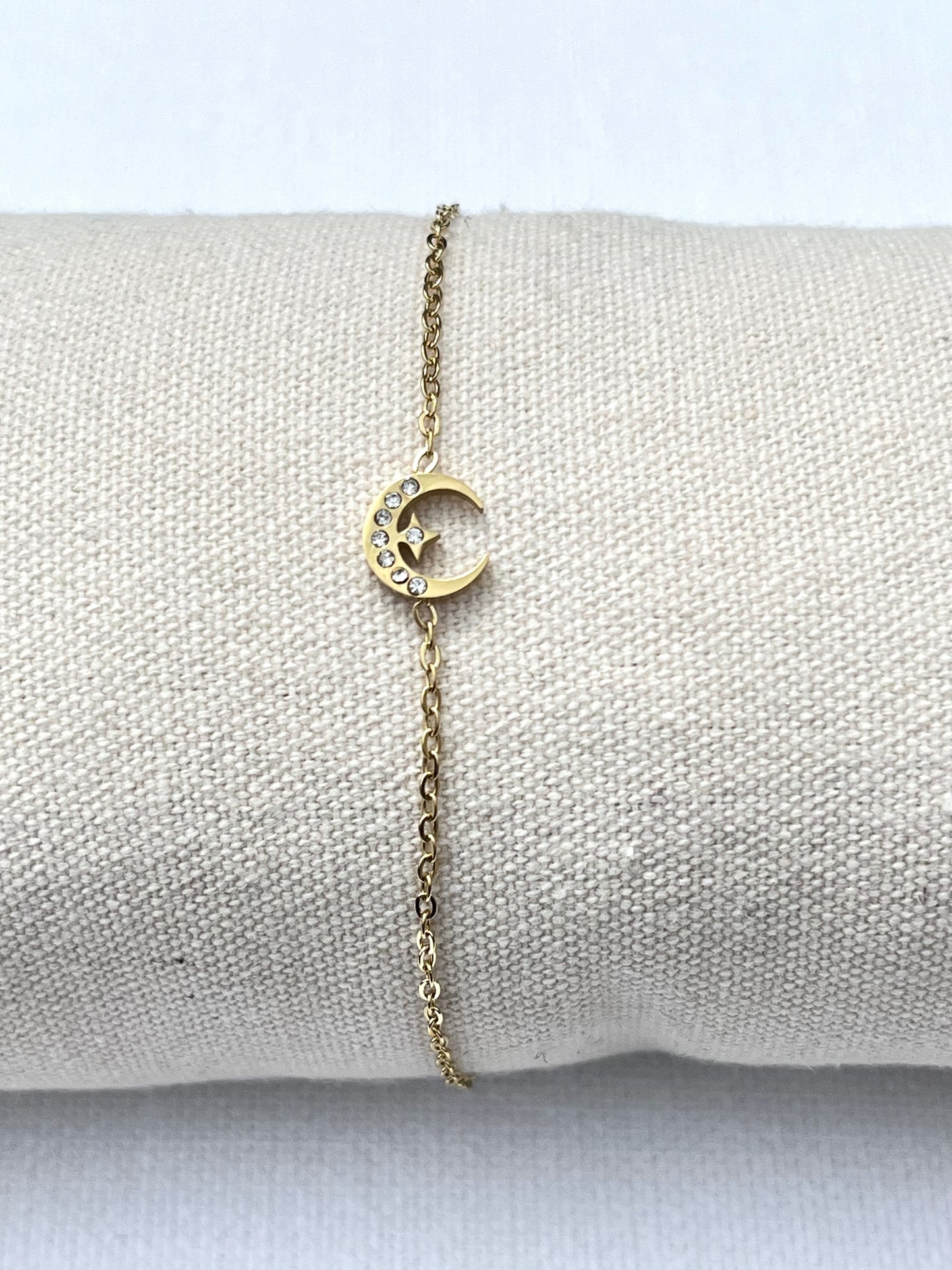 Bracelet en acier inoxydable, plaqué or et maille fine. Au milieu du bracelet une lune ornée de pierre de zirconium et au centre de cette lune une petite étoile elle même ornée d’une pierre de zirconium