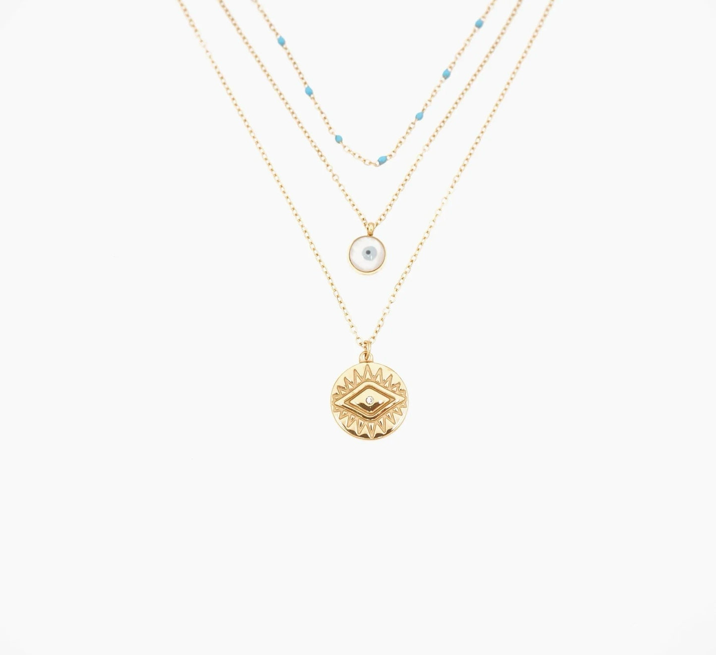 Adopte ce collier triple chaîne maille fine, en acier inoxydable et plaqué or, parfait pour affirmer ton style avec finesse. La première chaîne, ornée de petites perles turquoises, apporte une touche de fraîcheur et de couleur à ton cou. La deuxième chaîne met en lumière un pendentif œil en nacre, symbole de sagesse et de protection. La troisième chaîne, légèrement plus longue, est sublimée par un pendentif solaire doré gravé.