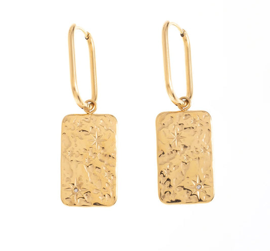 Fais briller ta personnalité avec ces boucles d’oreilles, en acier inoxydable et plaqué or, au design galactique. Leur plaque rectangulaire finement martelée, ornée de motifs étoilés, ajoute une touche cosmique à ton look. Porte-les pour un style audacieux.