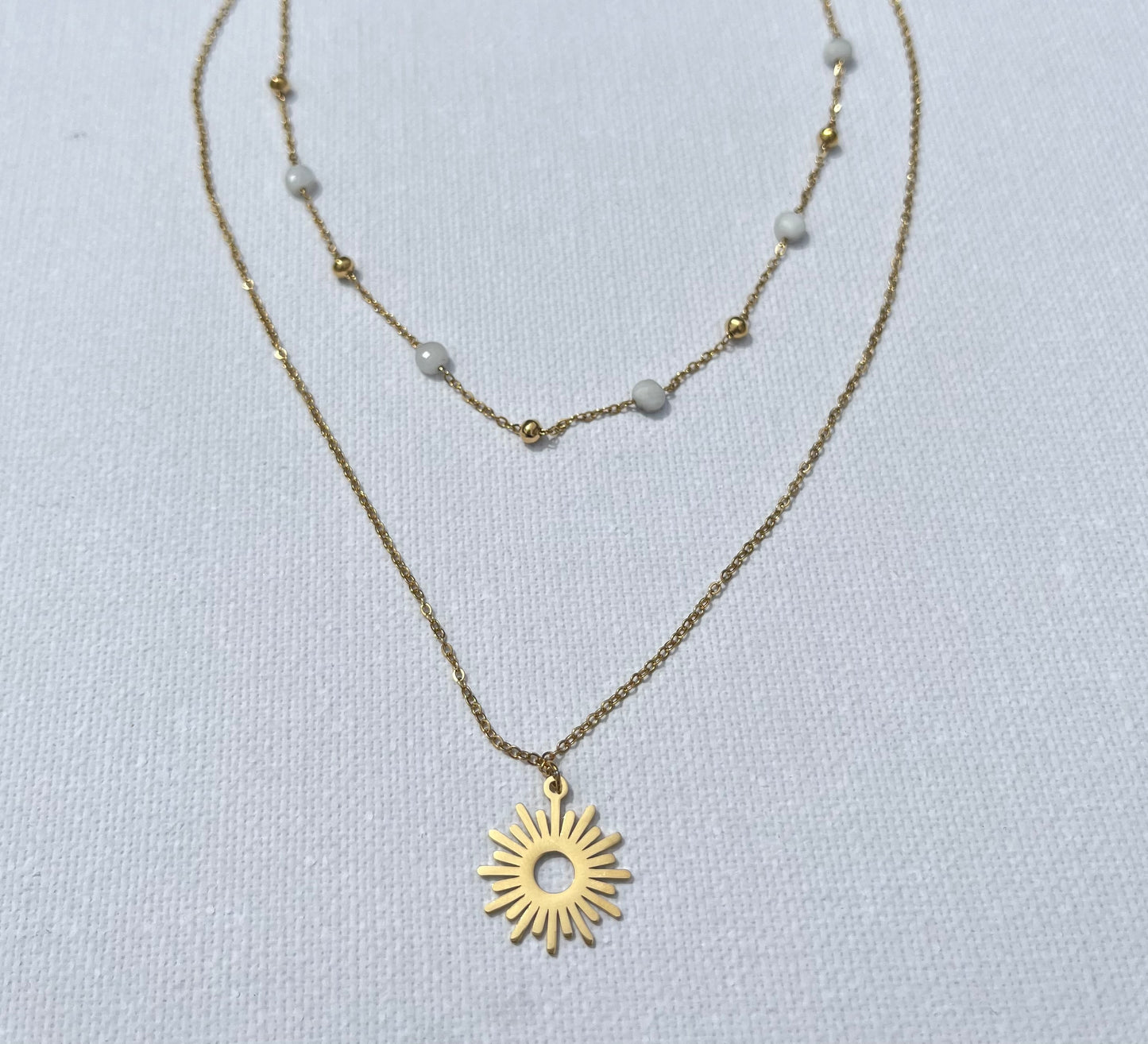 Craque pour ce bijou chic, en acier inoxydable et plaqué or, qui ne manquera pas de sublimer toutes tes tenues. Ce collier à double chaîne joue sur les contrastes avec finesse : une chaîne perlée délicate, agrémentée de petites perles blanches et de mini billes dorées, s’accorde parfaitement avec une chaîne plus simple et épurée, portant un pendentif en forme de soleil rayonnant. N'attends plus, ajoute cette pépite à ton panier et prépare-toi à rayonner !