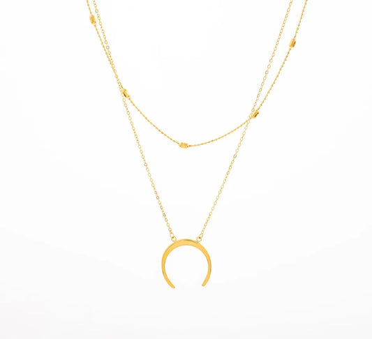 Ajoute une touche bohème à ton look avec ce superbe collier double rang, en acier inoxydable et plaqué or. Sa première chaîne est en maille forçat ornée de petites perles dorées, tandis que la seconde met en valeur un pendentif en croissant de lune, symbole de féminité et de renouveau. Porte-le seul pour un effet chic minimaliste ou superpose-le avec d'autres colliers pour un look plus audacieux.

