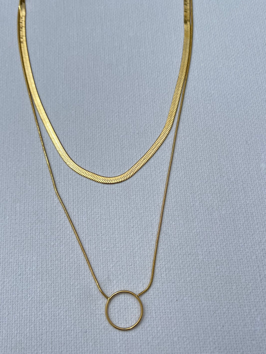 Succombe au charme de ce collier double, en acier inoxydable et plaqué or, parfait pour apporter une touche d'élégance à toutes tes tenues. La première chaîne, délicate et épurée, se distingue par sa maille miroir simple qui capte la lumière à chaque mouvement. La seconde chaîne, plus audacieuse avec sa maille serpent, est sublimée par un anneau central en plaqué or. Ce duo chic et minimaliste se marie parfaitement pour créer un look moderne et intemporel.