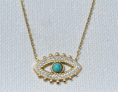Découvre notre collier multi-chaînes, en acier inoxydable et plaqué or. Ce bijou se compose de trois chaînes, chacune apportant sa touche unique. La première chaîne est une élégante maille chevron, ornée d'une perle turquoise. La seconde chaîne, plus courte, présente des maillons ovales entrelacés, créant un jeu de textures. Enfin, la troisième chaîne, plus fine et minimaliste, met en avant un pendentif en forme d’œil, serti de zircons et d'une pierre turquoise centrale.
