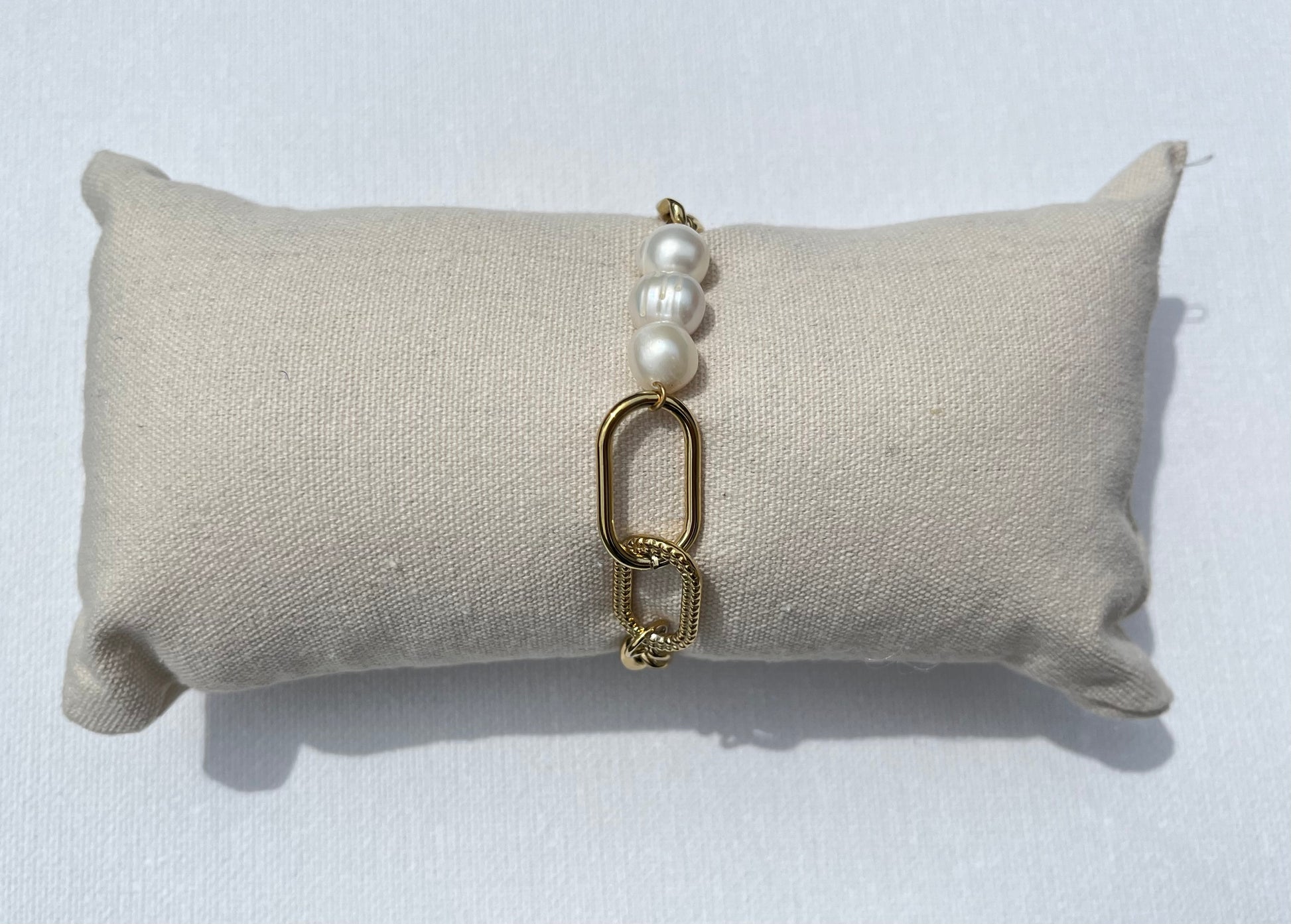 Ce bracelet en maille gourmette se distingue par son design unique et raffiné. Au centre, trois véritables perles d'eau douce apportent une touche d'élégance naturelle et deux ovales en plaqué or entrelacés, dont l'un est délicatement gravé de motifs en point. Un bijou sophistiqué et moderne, parfait pour rehausser n'importe quelle tenue avec une note d'élégance intemporelle.