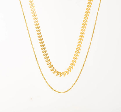 Ajoute une touche d'élégance à ton look avec ce collier à double chaîne, en acier inoxydable et plaqué or, parfait pour les femmes qui aiment le style épuré mais sophistiqué. Le premier rang est une chaîne chevron, connue pour sa fluidité et son éclat. La seconde chaîne en maille forçat, légère et discrète, idéale pour un look minimaliste mais chic. Ce collier est un véritable must-have pour te sublimer au quotidien !