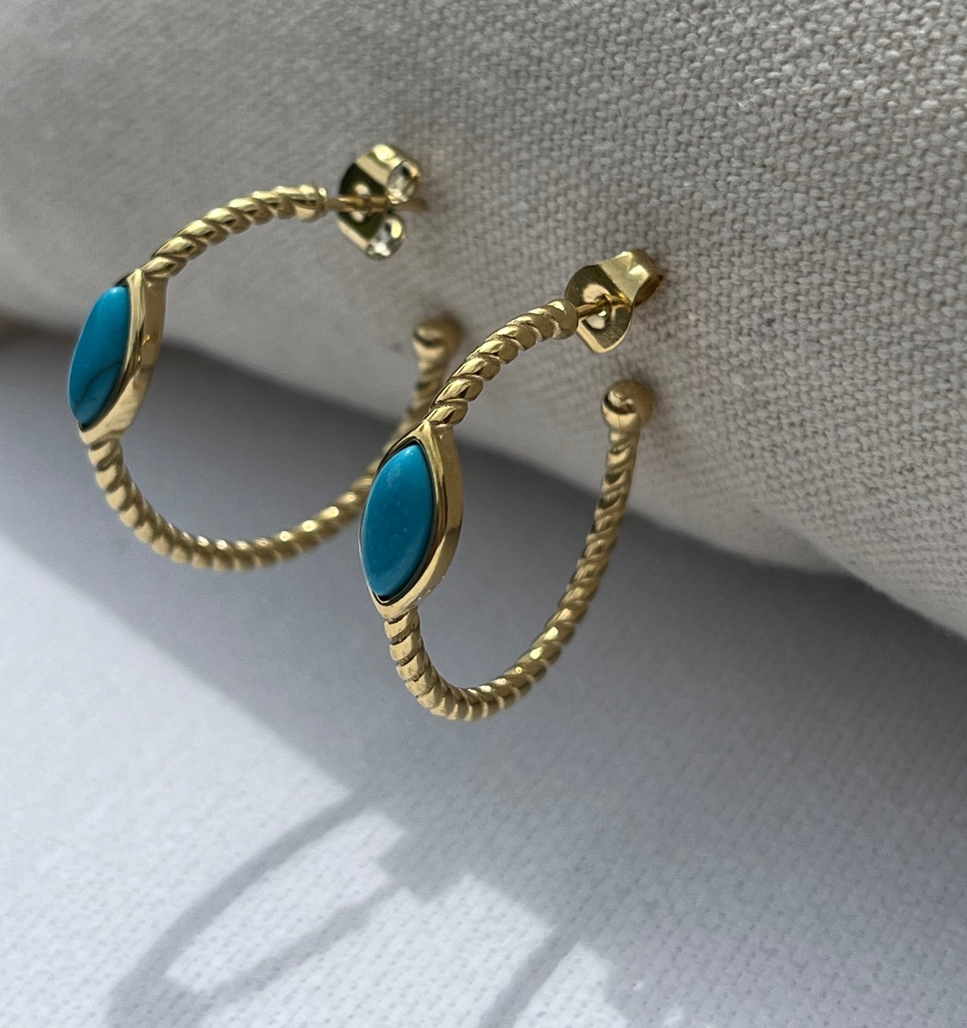 Ces créoles, en acier inoxydable et plaqué or, à la torsade élégante, ornées d'une pierre turquoise en forme d'amande, sont l'accessoire parfait pour apporter une touche d'exotisme à ton look. Le contraste subtil entre l'or et la turquoise crée un équilibre chic et lumineux, idéal pour illuminer tes tenues d'été ou ajouter un twist original à ton style quotidien.

