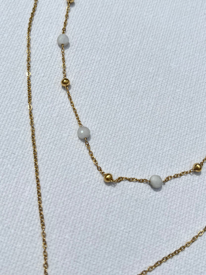 Craque pour ce bijou chic, en acier inoxydable et plaqué or, qui ne manquera pas de sublimer toutes tes tenues. Ce collier à double chaîne joue sur les contrastes avec finesse : une chaîne perlée délicate, agrémentée de petites perles blanches et de mini billes dorées, s’accorde parfaitement avec une chaîne plus simple et épurée, portant un pendentif en forme de soleil rayonnant. N'attends plus, ajoute cette pépite à ton panier et prépare-toi à rayonner !