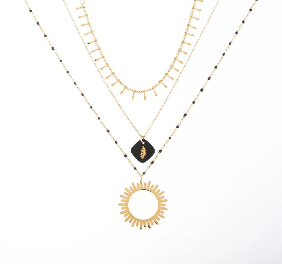 Collier triple, en acier inoxydable et plaqué or, qui saura sublimer ton style. Composé de trois chaînes. Ce bijou joue sur les contrastes pour un effet superposé. La première chaîne, ornée de petits maillons pendants, apporte une touche d'éclat. La deuxième chaîne, parée de perles noires et d'un pendentif en forme de feuille dorée sur un fond noir, ajoute une note bohème et chic. Enfin, la dernière chaîne met en valeur un magnifique pendentif en forme de soleil