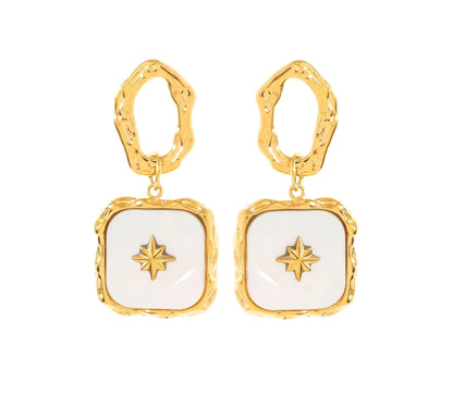 Succombe au charme de ces boucles d'oreilles, en acier inoxydable et plaqué or. Ces boucles affichent une structure irrégulière et organique qui ajoute une touche artistique à ton look. Le pendentif carré, orné d’un blanc nacré, est sublimé par un motif étoilé doré en son centre. Leur design unique fera de ce bijou une pièce maîtresse de ta collection.