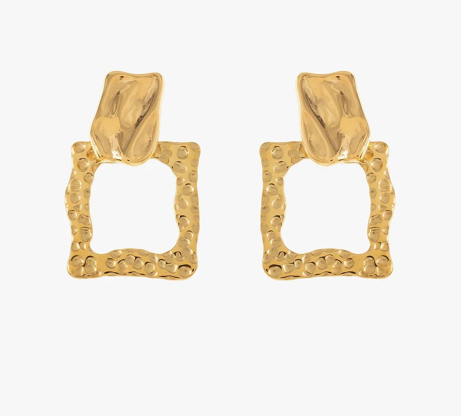 Découvre ces boucles d'oreilles élégantes, en acier inoxydable et plaqué or. Elles arborent une forme géométrique avec un design texturé. La partie supérieure est subtilement sculptée, évoquant un effet martelé, tandis que la base présente un carré ouvert aux bords irréguliers, créant un contraste visuel. Léger et confortable, ce bijou se porte facilement au quotidien. Adopte ce bijou unique pour ajouter une pointe d'originalité à ton look.