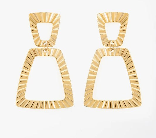 Découvre ces boucles d’oreilles forme de trapèze, en acier inoxydable et plaqué or, parfaites pour sublimer ton look. Ces bijoux affichent un design géométrique ultra-tendance, avec deux trapèzes emboîtés qui créent un effet de mouvement et de légèreté. Le premier trapèze, plus petit et délicat, s’accroche à l’oreille, tandis que le second est plus grand. Les bords de ces trapèzes sont finement texturés, avec des stries gravées.