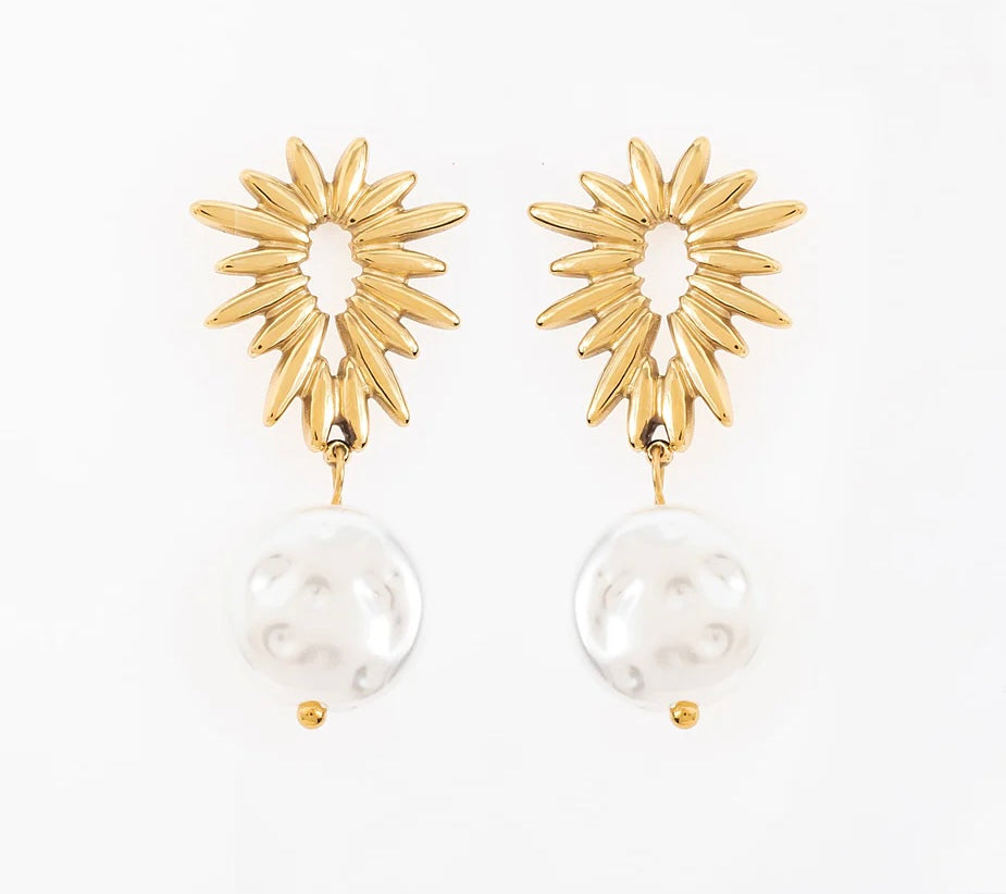 Ose ces boucles d’oreilles, en acier inoxydable et plaqué or, avec un design unique qui allie audace et élégance. La partie supérieure, en forme de soleil, évoque puissance et éclat. Juste en dessous, une élégante perle d’eau douce suspendue. Elles se portent aussi bien seules qu’avec d’autres bijoux pour un effet superposé. C’est l’accessoire parfait pour sublimer ta féminité et affirmer ta personnalité.